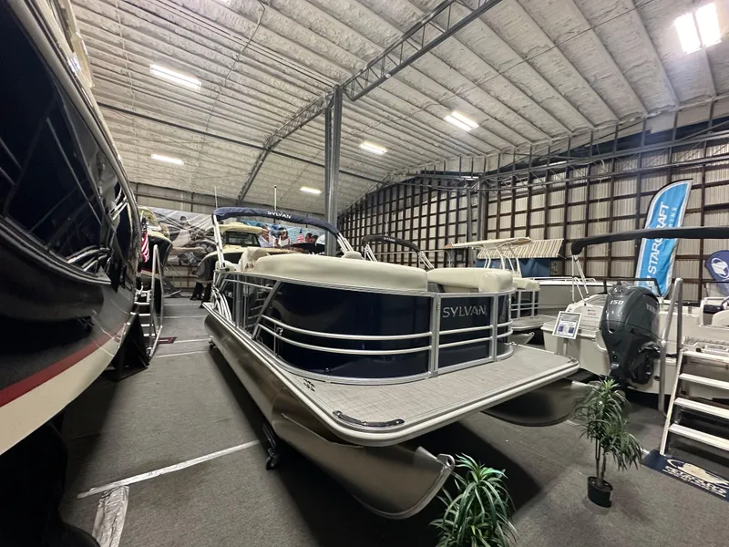 Slide: The Image of 2026 Sylvan Mirage 8520 LZ pontoon boat displayed indoors at a showroom. - 6