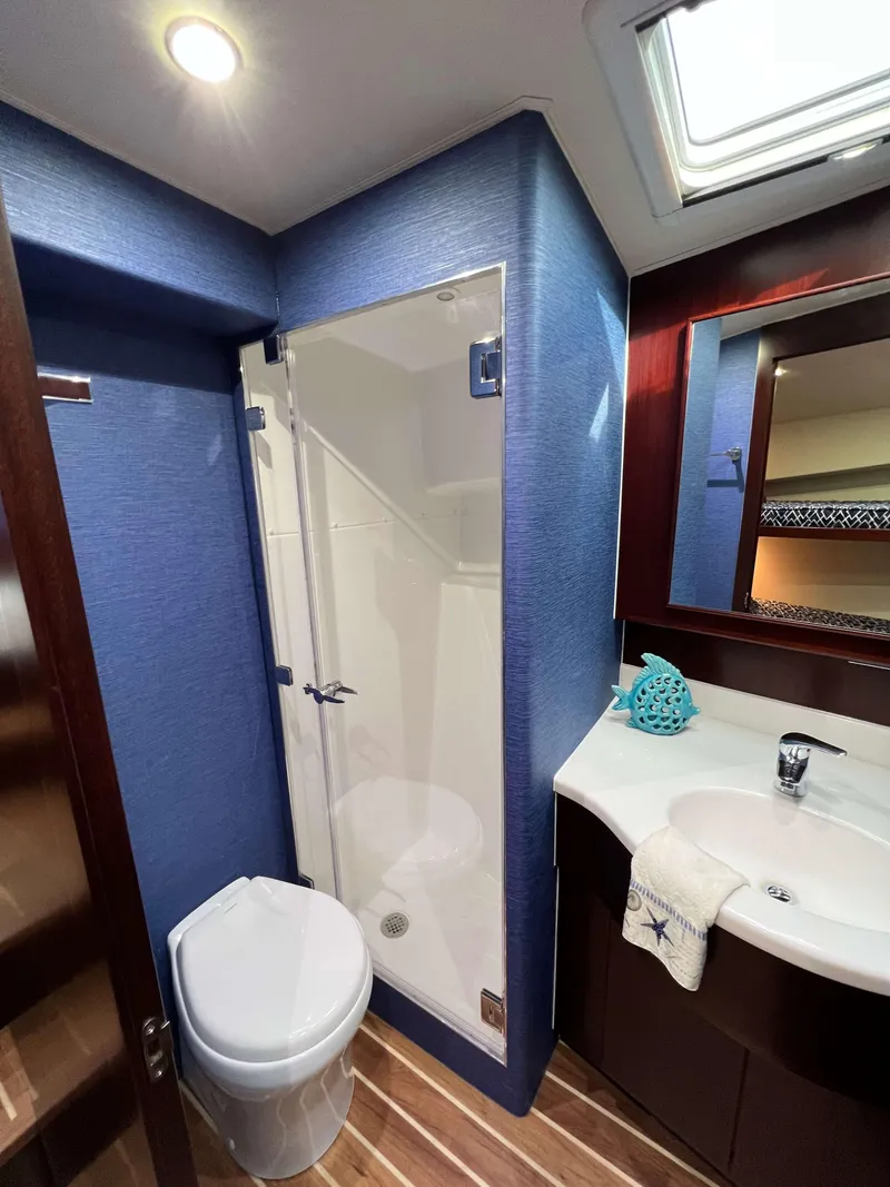 Slide: The Image of 2025 Henriques 42 Flybridge bathroom with modern fixtures, blue walls, and wooden flooring. - 17