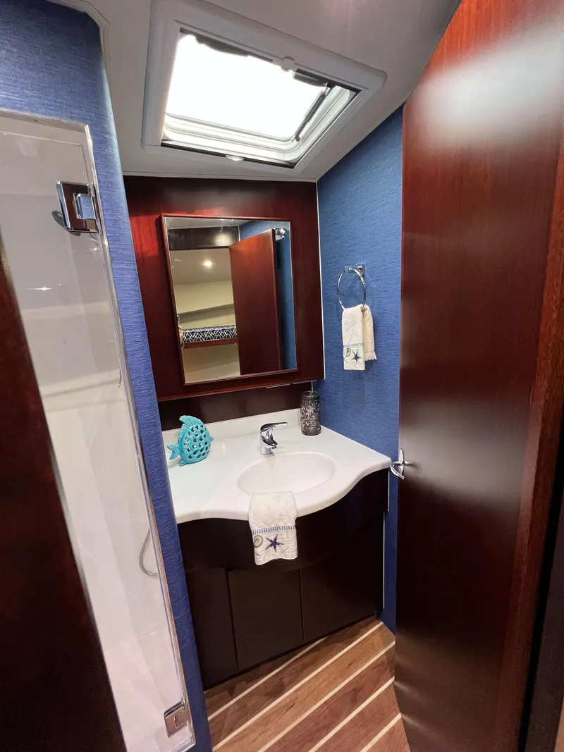 Slide: The Image of 2025 Henriques 42 Flybridge bathroom with modern fixtures, wooden accents, and blue walls. - 18