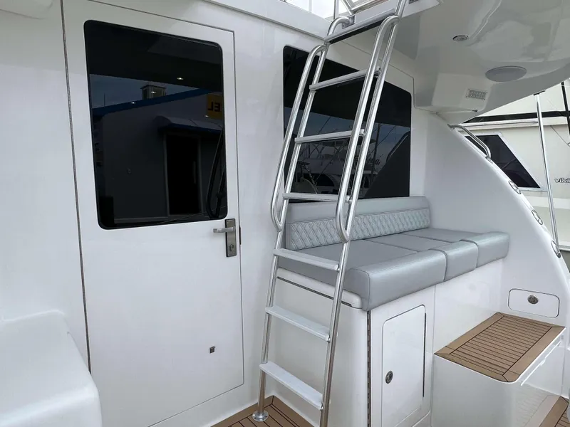 Slide: The Image of 2025 Henriques 42 Flybridge yacht with ladder, cushioned seating, and sleek white exterior. - 6