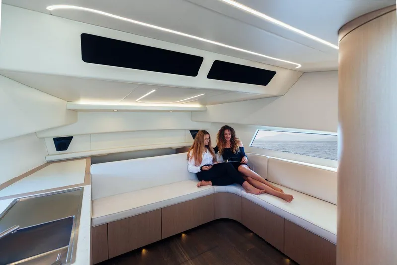 Slide: The Image of Modern interior of Maori 54 yacht, 2020 model, with two women relaxing on a white sofa. - 22