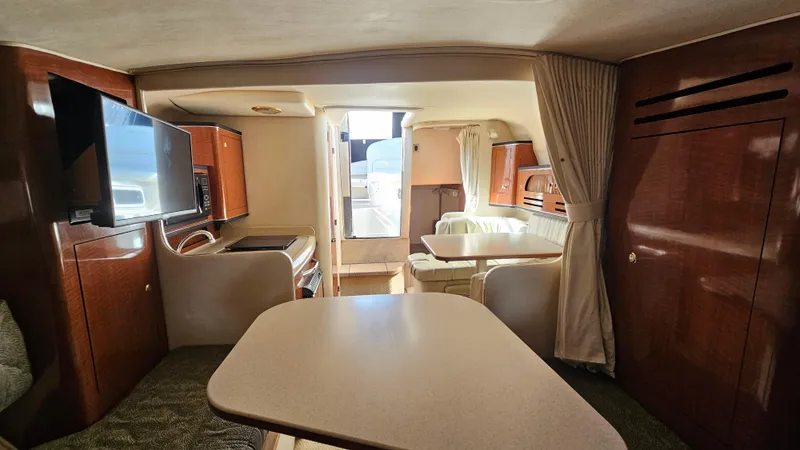 Slide: The Image of Interior of 2003 Sea Ray 280 Sundancer with dining area, TV, and wood cabinetry. - 14