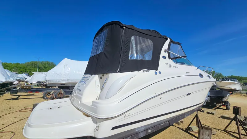 Slide: The Image of 2003 Sea Ray 280 Sundancer boat with black canvas cover on dry dock. - 2