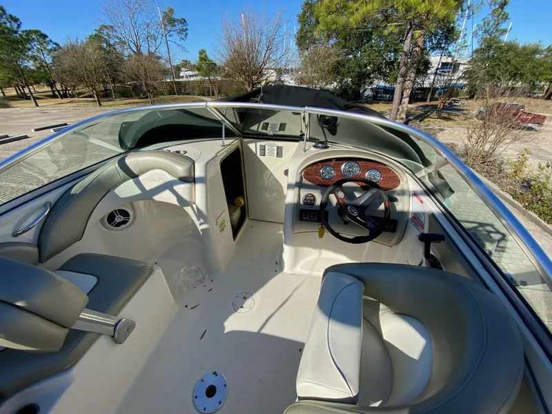 Slide: The Image of 2006 Sea Ray 200 Sundeck interior with steering wheel and seating, parked outdoors. - 6