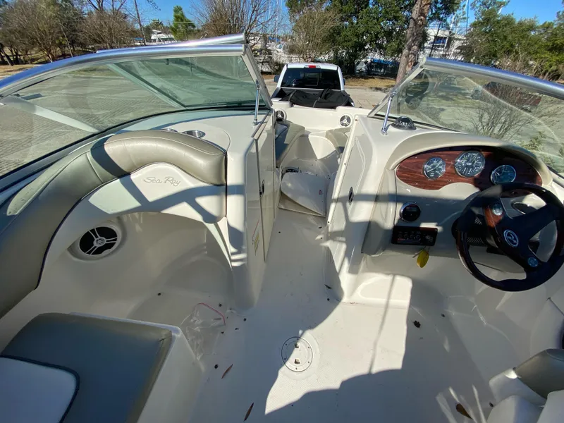 Slide: The Image of 2006 Sea Ray 200 Sundeck interior with steering wheel and seating, parked outdoors. - 9