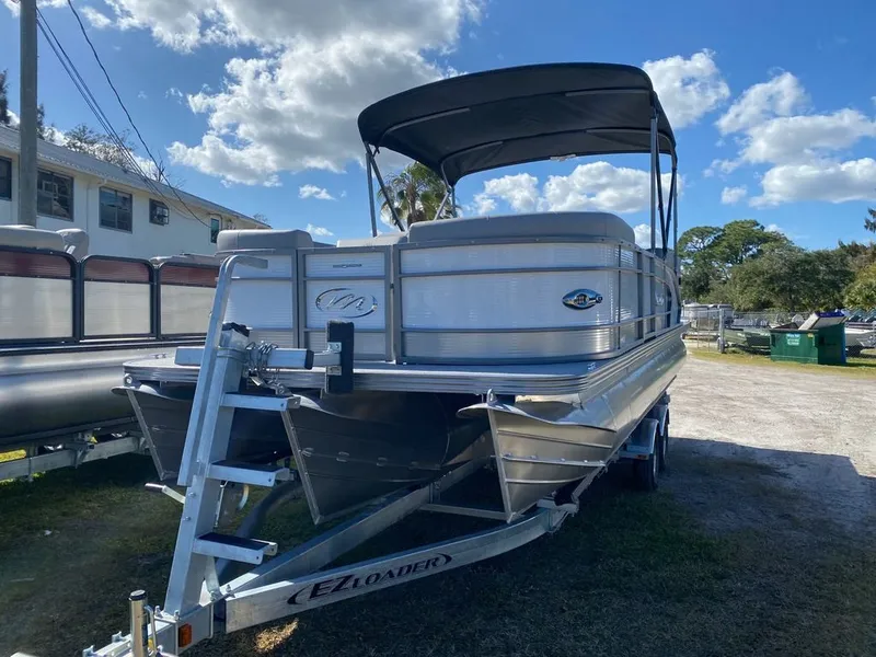 Slide: The Image of 2022 Manitou 23 Encore RF VP pontoon boat on EZ Loader trailer under a blue sky. - 1