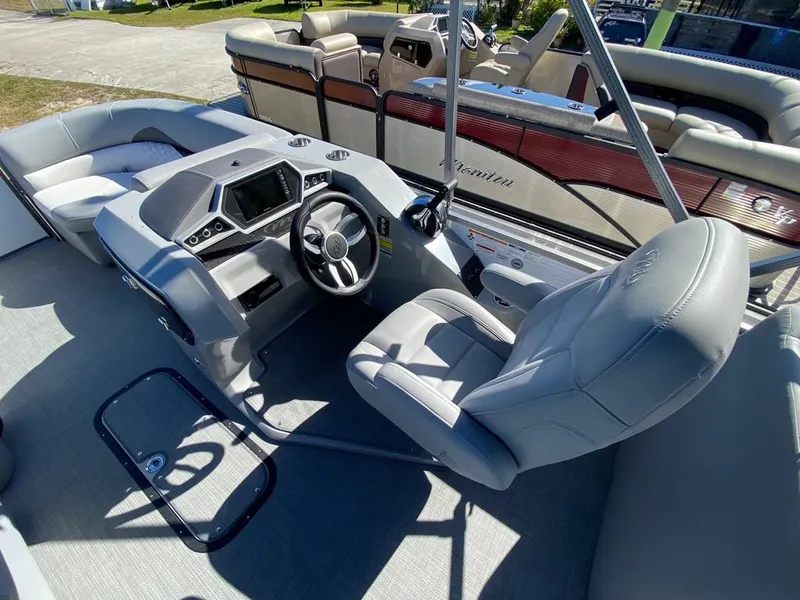 Slide: The Image of 2022 Manitou 23 Encore RF VP boat interior with steering console and seating. - 12