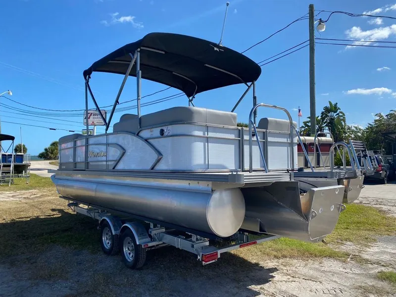Slide: The Image of 2022 Manitou 23 Encore RF VP pontoon boat on trailer under blue sky. - 4