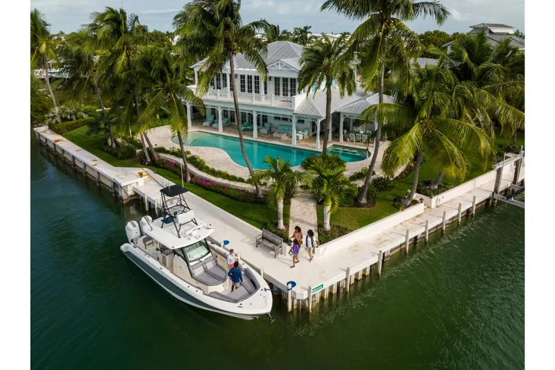 Slide: The Image of 2023 Boston Whaler 360 Outrage docked by a luxurious waterfront home with a pool. - 48