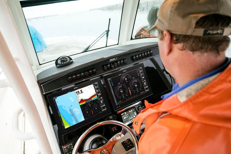 Slide: The Image of Man operating 2024 Boston Whaler 330 Outrage boat with advanced navigation system. - 10