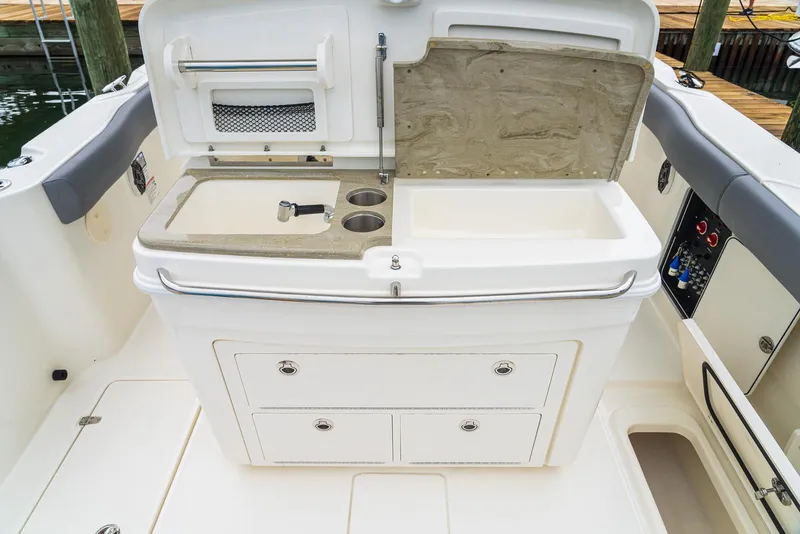 Slide: The Image of 2024 Boston Whaler 330 Outrage boat interior with sink and storage compartments. - 14