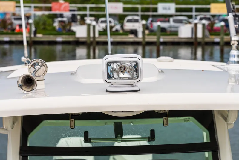Slide: The Image of 2024 Boston Whaler 330 Outrage boat spotlight and horn detail at marina. - 17