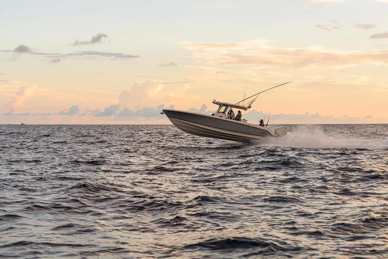 Slide: The Image of 2024 Boston Whaler 330 Outrage speeding on ocean at sunset. - 19