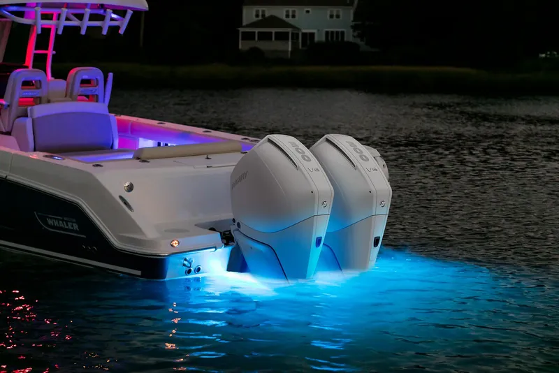 Slide: The Image of 2024 Boston Whaler 330 Outrage with illuminated twin engines on water at night. - 8