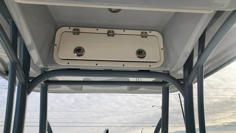 Slide: The Image of 2022 Cobia 220 CC boat T-top storage compartment under cloudy sky. - 11