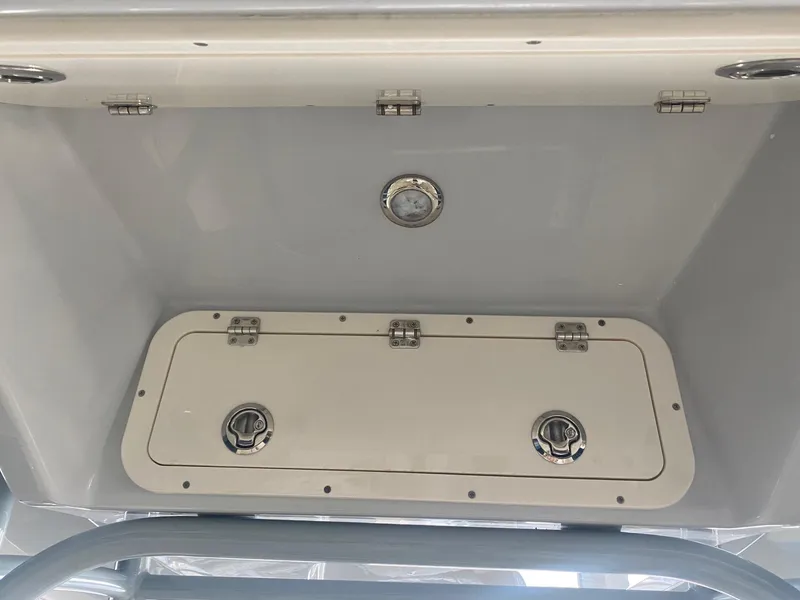 Slide: The Image of 2022 Cobia 220 CC storage compartment with secure latches and drainage. - 12