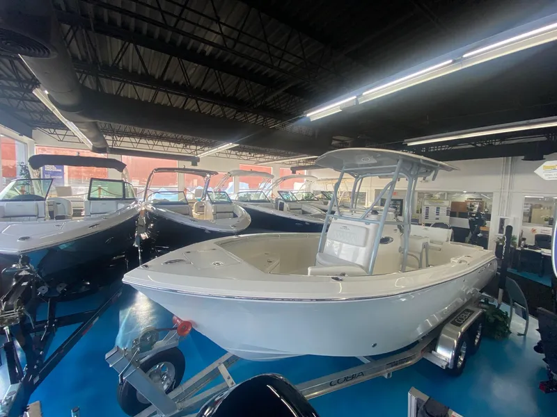 Slide: The Image of 2022 Cobia 220 CC center console boat displayed in a showroom. - 2