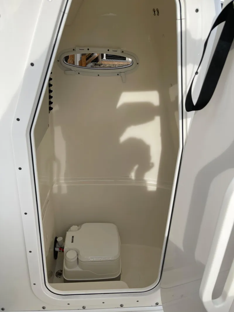 Slide: The Image of 2022 Cobia 220 CC boat interior with a compact marine toilet. - 23