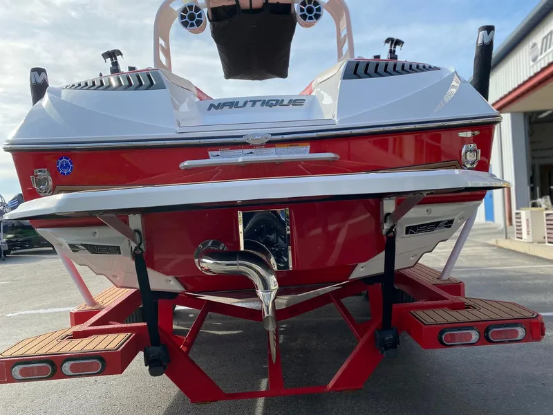 Slide: The Image of 2018 Nautique G23 boat rear view, red and white design, parked on a trailer. - 11