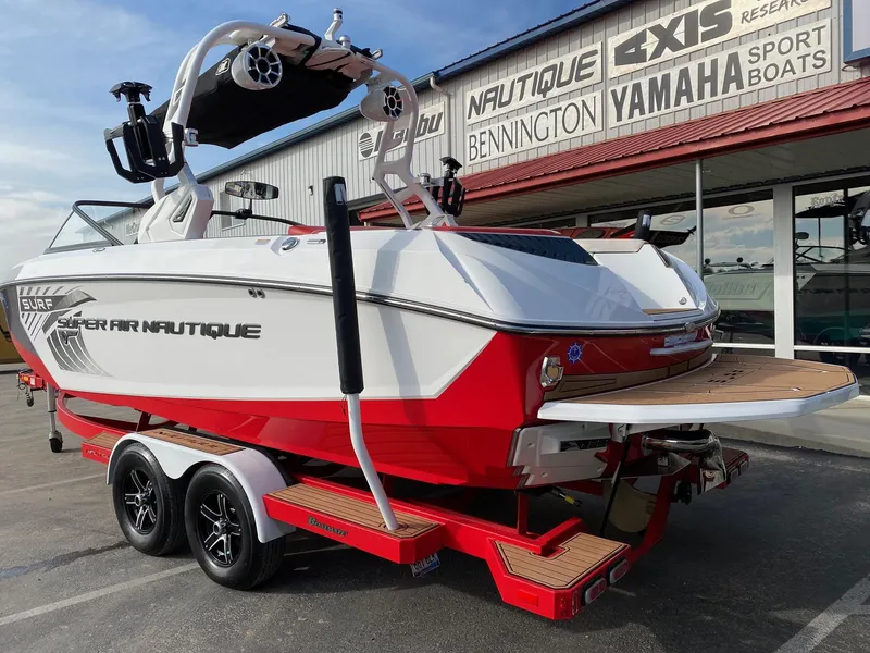 Slide: The Image of 2018 Nautique G23 boat on trailer, red and white design, parked outside dealership. - 13