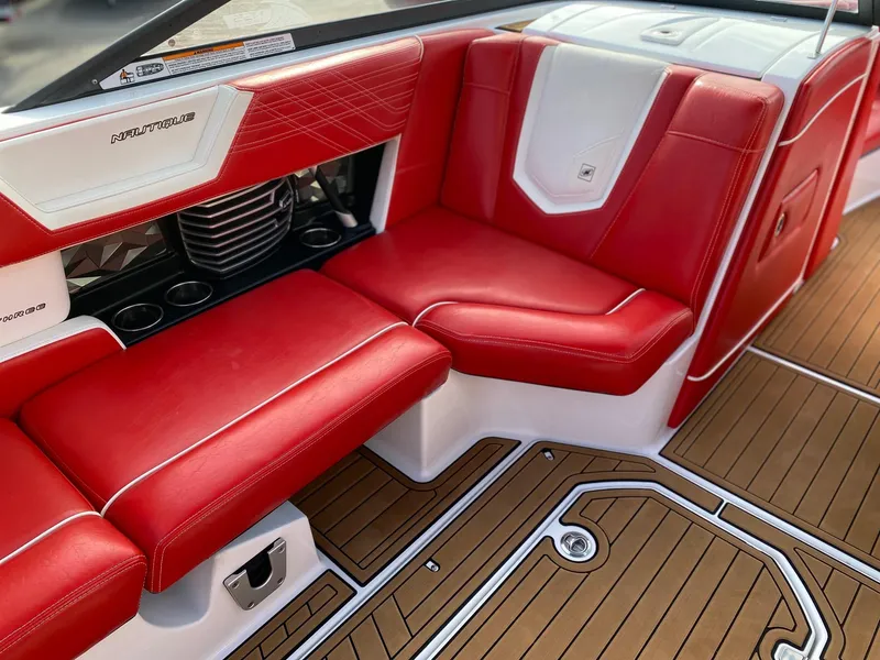 Slide: The Image of 2018 Nautique G23 interior with red and white seating, teak flooring, and cup holders. - 21
