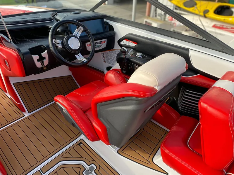 Slide: The Image of 2018 Nautique G23 boat interior with red and white seating, modern dashboard, and wood-style flooring. - 22