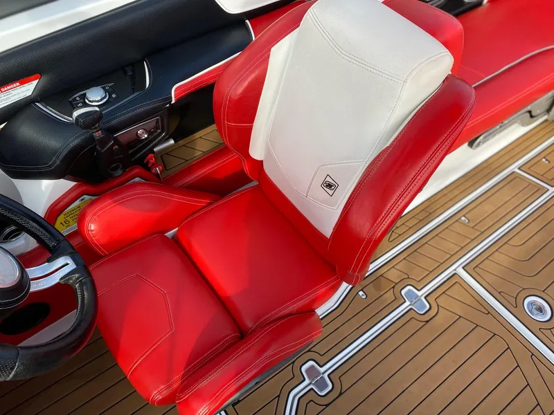 Slide: The Image of Red and white captain's seat in 2018 Nautique G23 boat interior. - 23