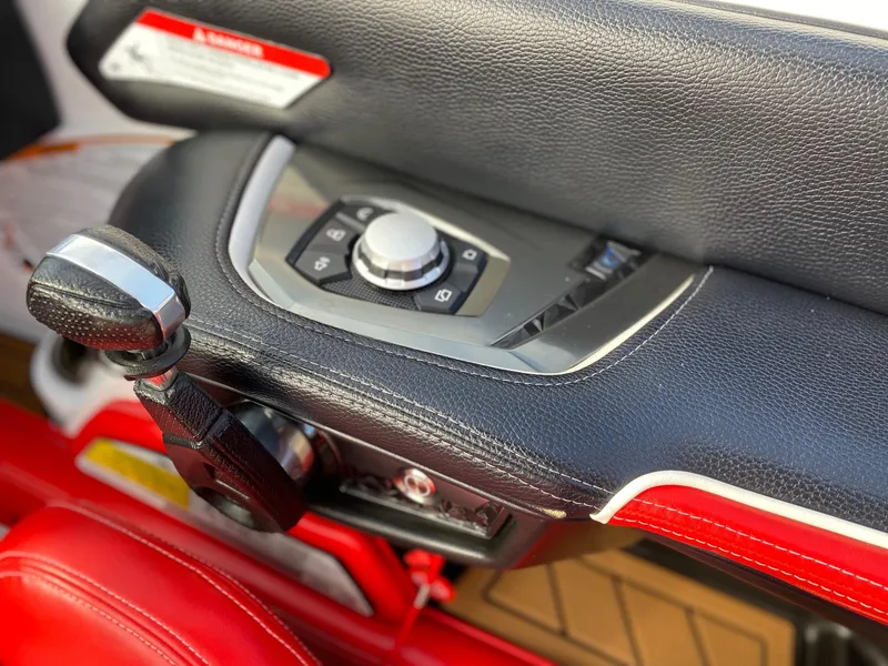 Slide: The Image of 2018 Nautique G23 boat control panel with leather trim and red accents. - 25
