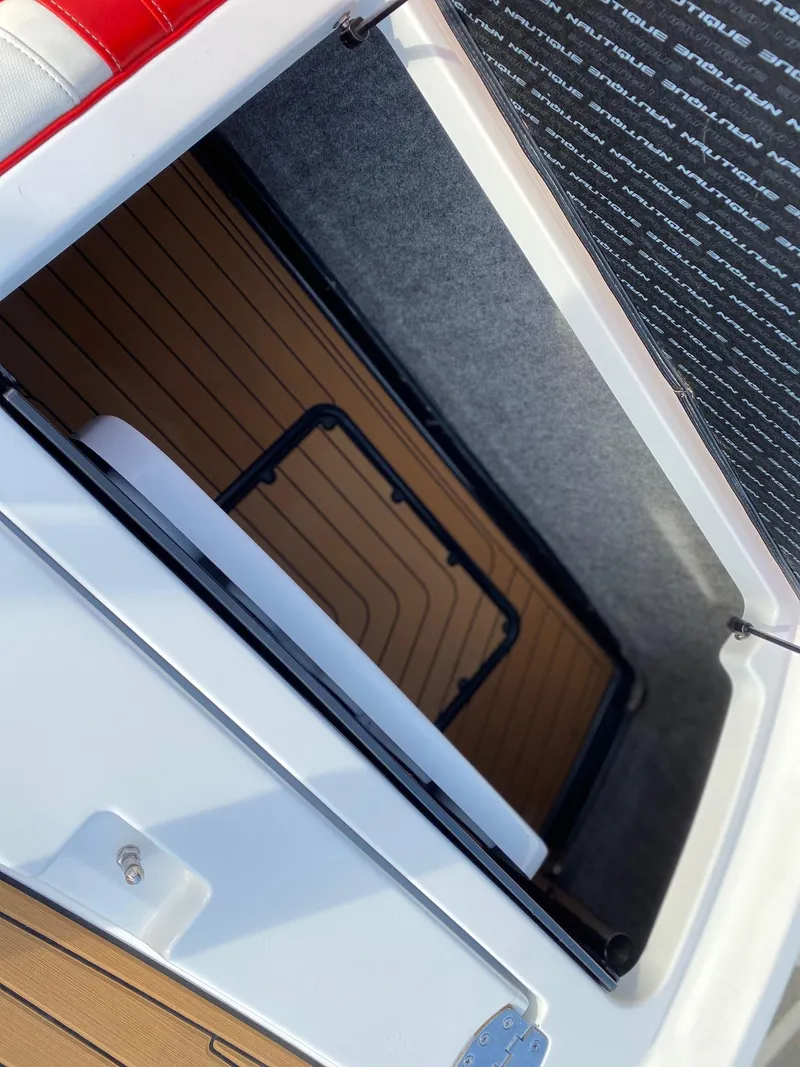 Slide: The Image of 2018 Nautique G23 storage compartment with teak flooring and red upholstery. - 34