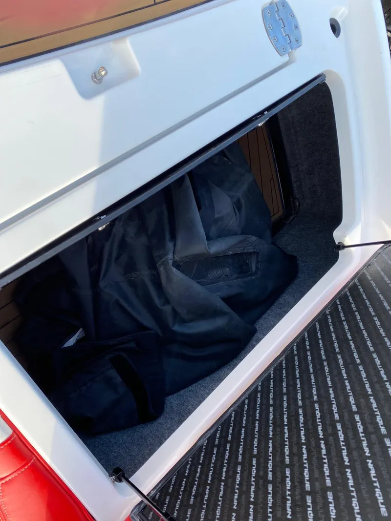 Slide: The Image of 2018 Nautique G23 storage compartment with black bag inside. - 35