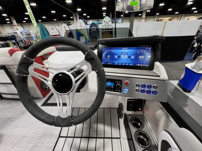 Slide: The Image of 2022 Montara SURF BOSS 23 dashboard with steering wheel and digital display at a boat show. - 15