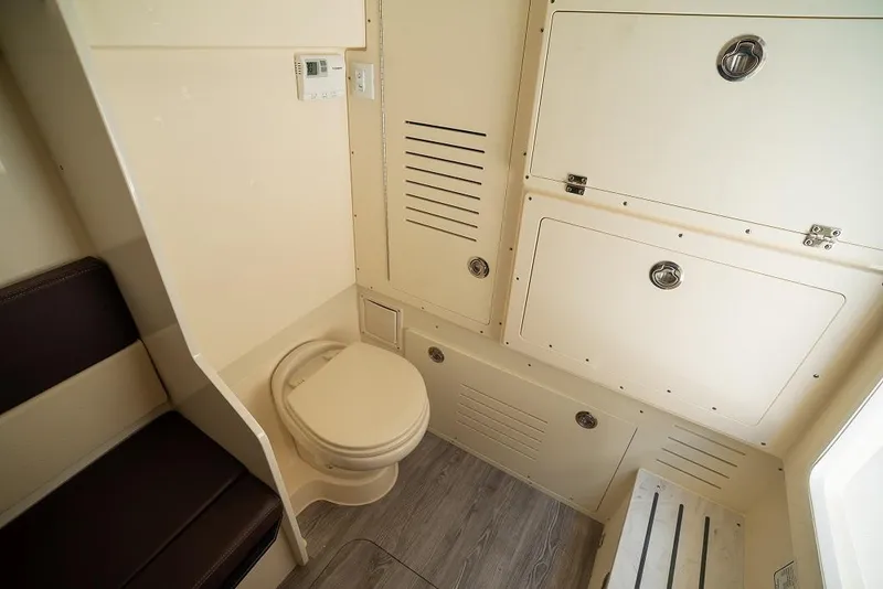 Slide: The Image of 2025 Scout 330 LXF boat interior bathroom with toilet and storage compartments. - 27