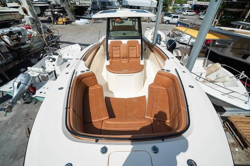 Slide: The Image of 2025 Scout 330 LXF boat with luxurious brown leather seating in a marina. - 32