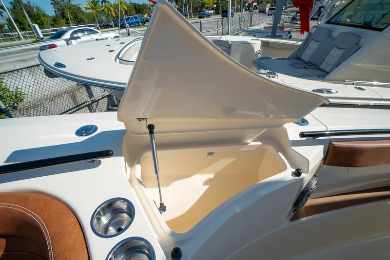 Slide: The Image of 2025 Scout 330 LXF boat with open storage compartment and cup holders. - 44