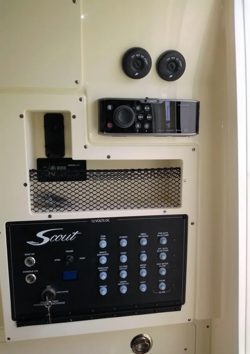 Slide: The Image of 2025 Scout 305 LXF control panel with Fusion stereo system and 12V DC switches. - 12