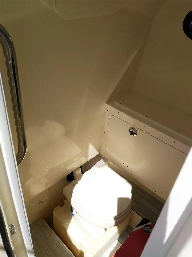 Slide: The Image of 2025 Scout 277 LXF boat interior bathroom with toilet and storage compartment. - 11