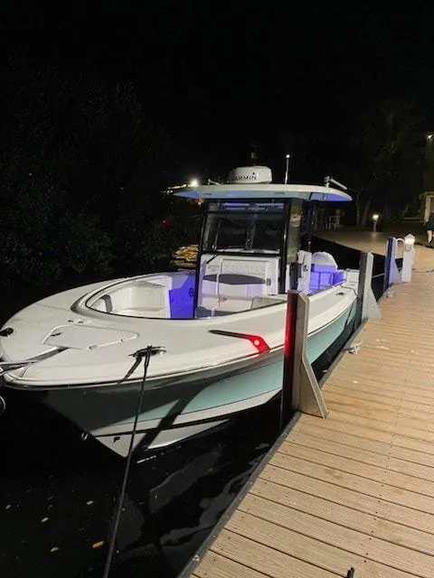 Slide: The Image of 2020 Robalo 302 boat docked at night with blue interior lights. - 0