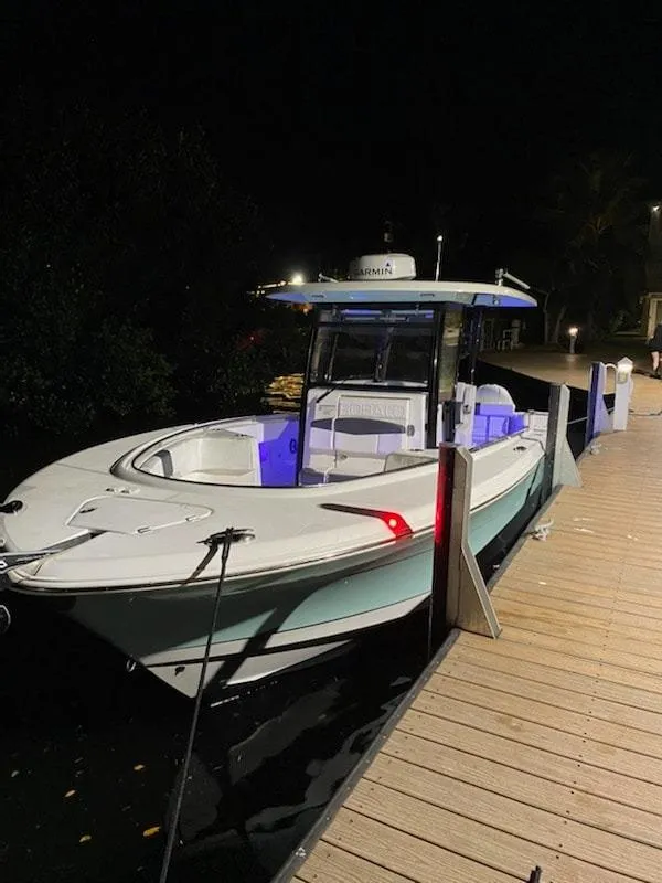 Slide: The Image of 2020 Robalo 302 boat docked at night with blue interior lights. - 4