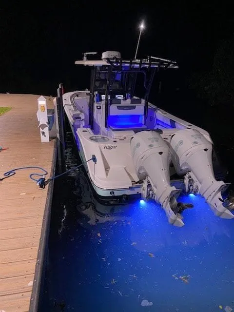 Slide: The Image of 2020 Robalo 302 boat docked at night with blue underwater lights. - 6