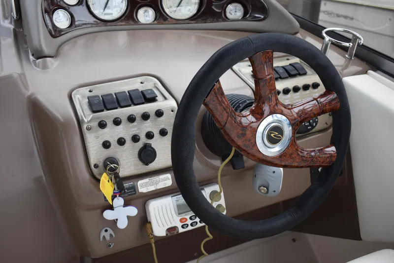 Slide: The Image of 2005 Regal Commodore 2665 boat dashboard with wood-accented steering wheel and control panel. - 26