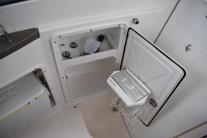Slide: The Image of 2005 Regal Commodore 2665 boat interior storage compartment with open door and cleaning supplies. - 47