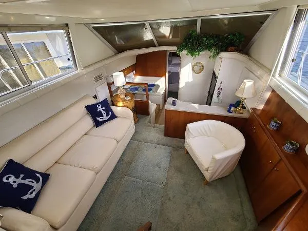 Slide: The Image of 1995 Silverton 34 Aft Cabin Motor Yacht interior with cream sofa, chair, and nautical decor. - 17