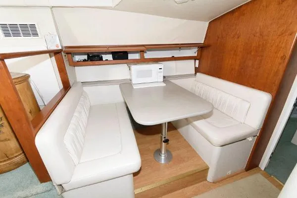 Slide: The Image of 1995 Silverton 34 Aft Cabin Motor Yacht interior dining area with booth seating and microwave. - 21
