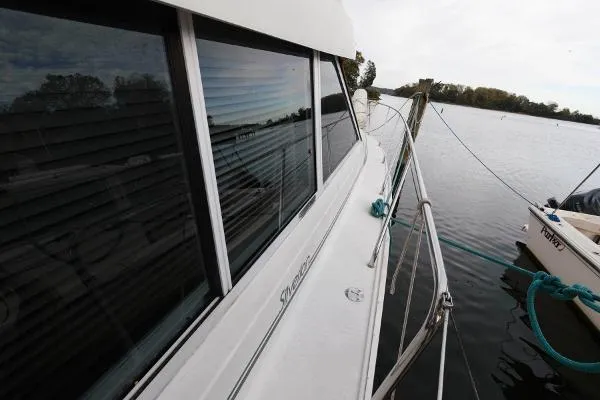 Slide: The Image of 1995 Silverton 34 Aft Cabin Motor Yacht docked by a lake. - 4