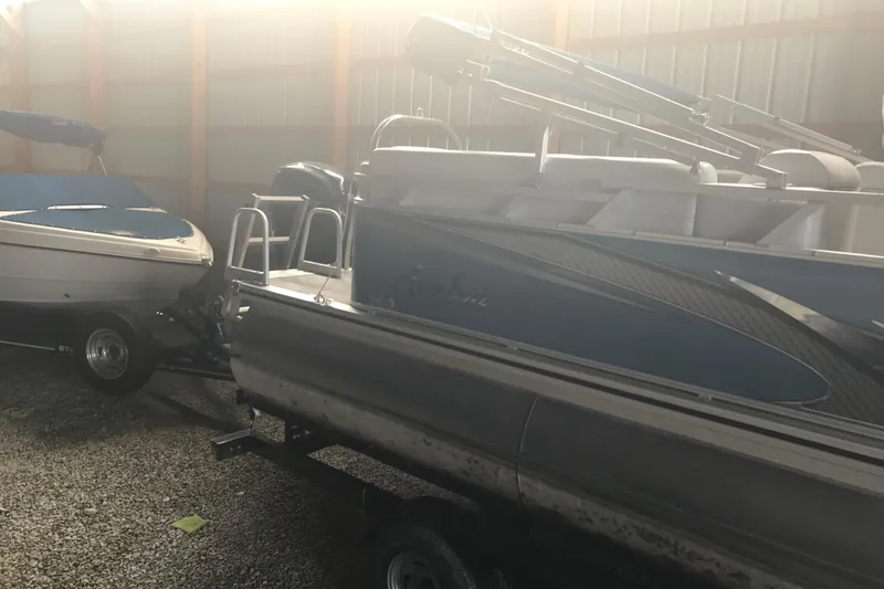 Slide: The Image of 2022 Avalon VENTURE QUAD LOUNGE pontoon boat in storage, alongside another boat. - 11