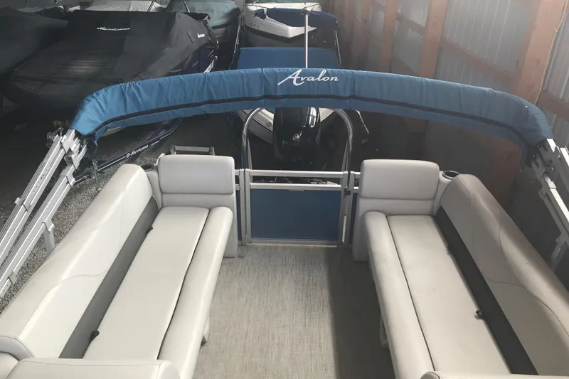 Slide: The Image of 2022 Avalon VENTURE QUAD LOUNGE pontoon boat with blue canopy in storage. - 20