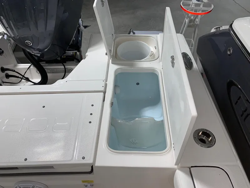 Slide: The Image of 2024 Robalo 246 Cayman boat with open storage compartments and engine in view. - 6