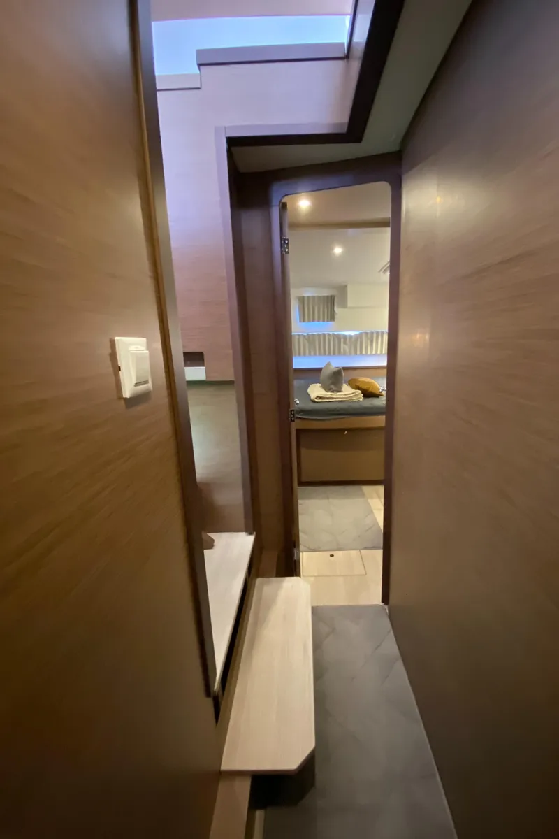 Slide: The Image of Interior hallway of 2022 Lagoon 42 yacht, featuring modern wood paneling and sleek design. - 13