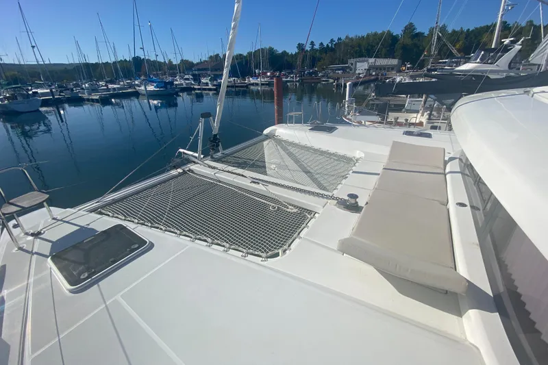 Slide: The Image of 2022 Lagoon 42 catamaran docked at marina, featuring spacious deck and netting. - 2