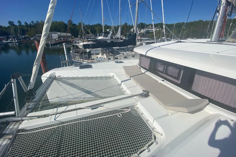 Slide: The Image of 2022 Lagoon 42 catamaran docked in a marina, featuring spacious deck and netting. - 3